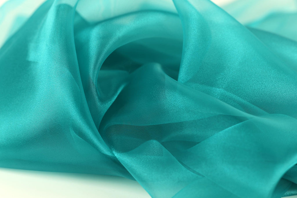 The image is a close-up of a fabric with a turquoise color, appearing soft and flowing.