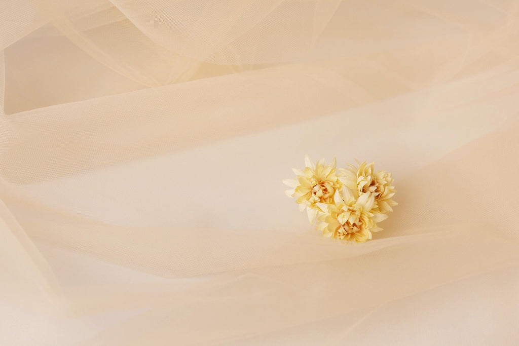 A single yellow flower is resting on a light beige fabric, creating a simple and elegant composition.