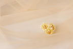 A single yellow flower is resting on a light beige fabric, creating a simple and elegant composition.