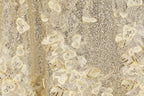 The image is a close-up of a fabric with a gold and white floral pattern, featuring small sequins and beads.