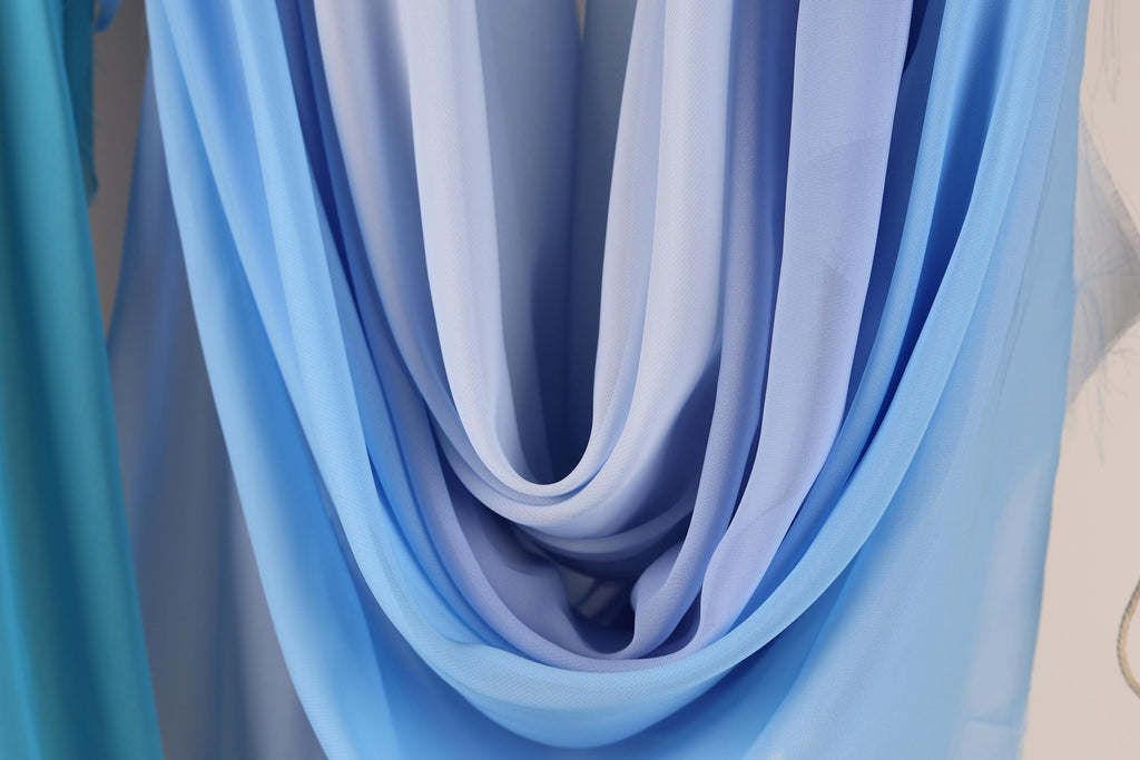 a close-up view of a blue and white fabric, possibly a scarf or garment, with a soft, flowing texture.