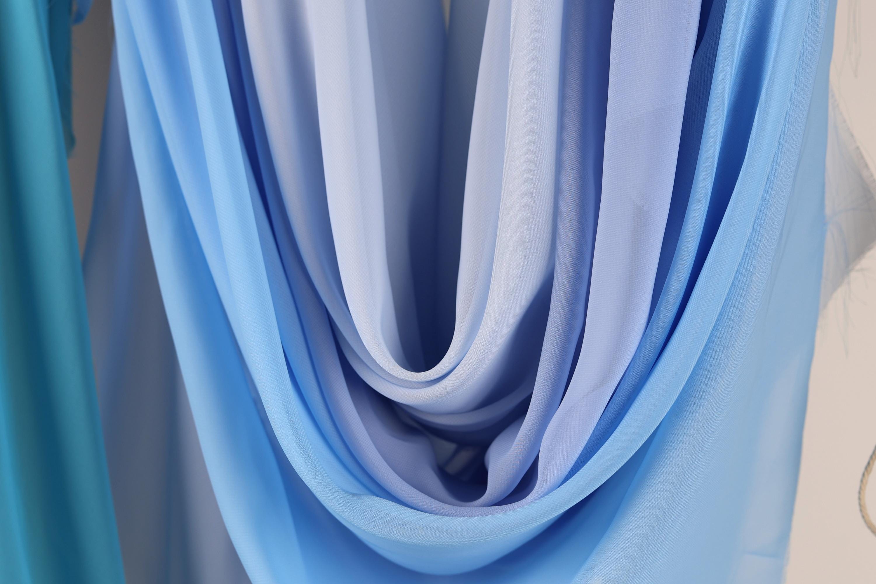 a close-up view of a blue and white fabric, possibly a scarf or garment, with a soft, flowing texture.