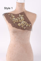 A mannequin with a brown fabric piece featuring gold floral embroidery on its chest.