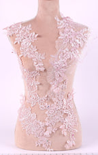 A mannequin is wearing a dress with intricate pink lace details, including floral and leaf patterns.