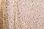 a close-up view of a delicate, intricately embroidered fabric with a floral pattern. The fabric appears to be made of sheer material, with a blend of gold and pink colors. The pattern is composed of numerous small flowers and leaves, creating a visually appealing and detailed design. The fabric is spread across the entire frame, showcasing its intricate design and the craftsmanship involved in its creation.