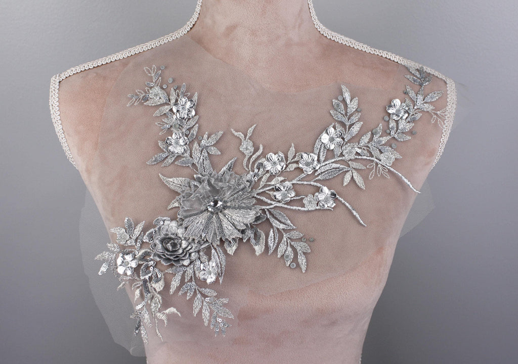 A mannequin torso with a delicate, intricate silver floral embroidery on the bust area.