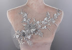 A mannequin torso with a delicate, intricate silver floral embroidery on the bust area.