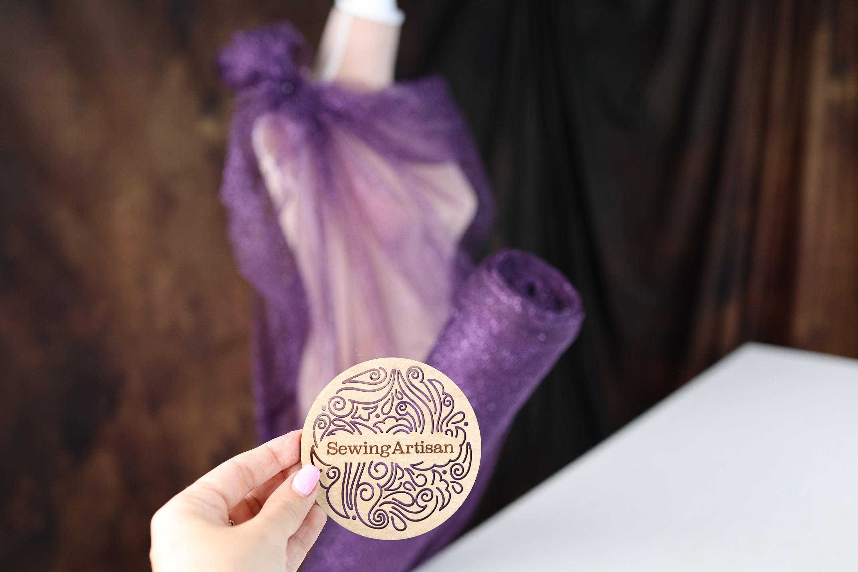 a person holding a wooden plaque with a purple dress on it