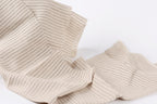 a close-up view of a fabric with a striped pattern, featuring a mix of horizontal and vertical stripes in varying shades of beige.