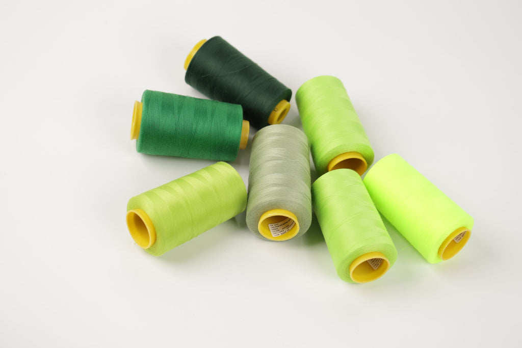 a collection of green and yellow thread spools arranged on a white background.