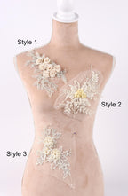 A mannequin with three different styles of lace or floral embellishments displayed on its bust.