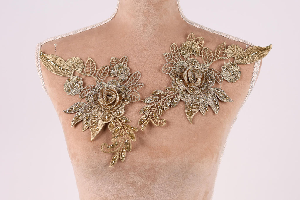 a mannequin with two gold floral pieces on its shoulders.