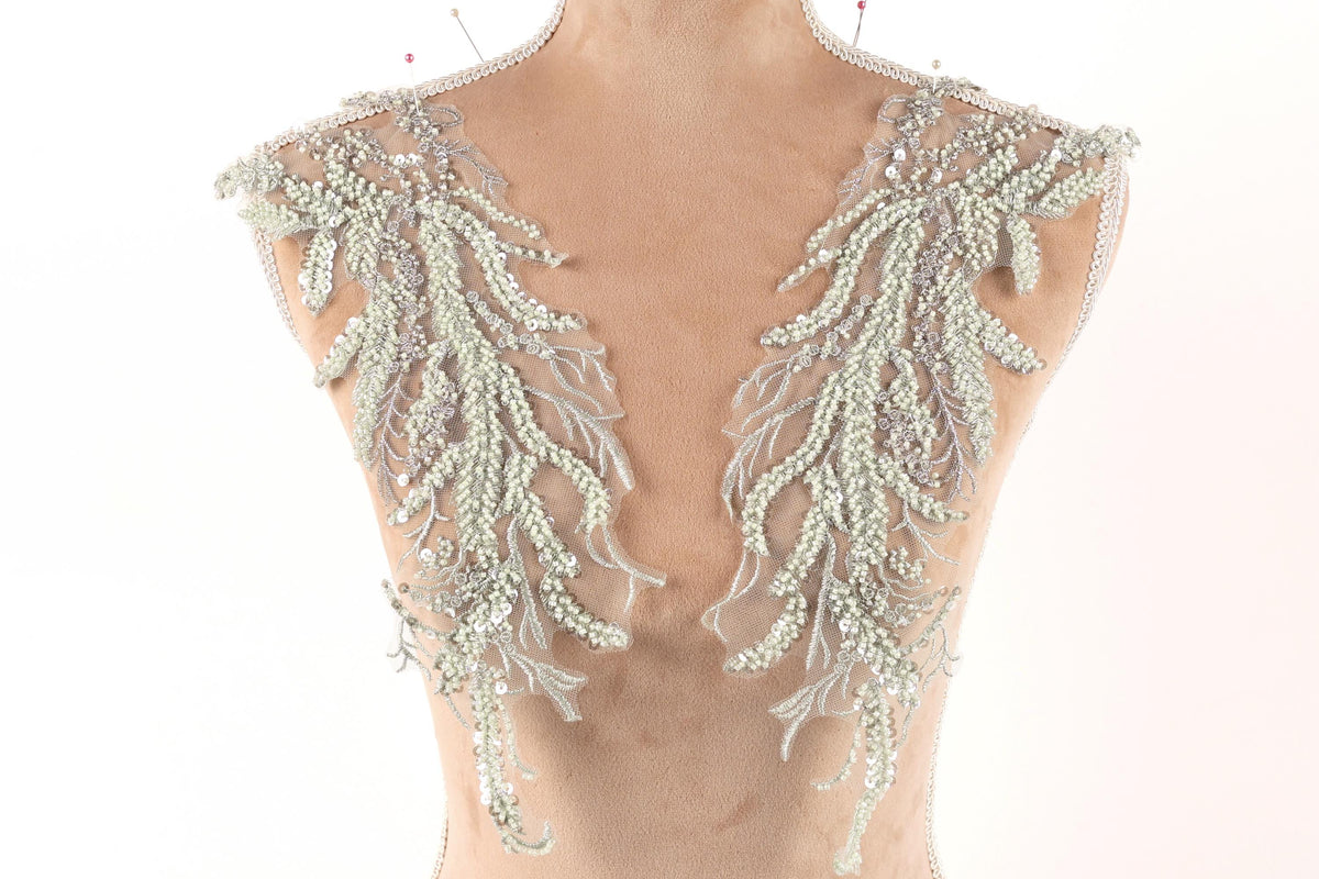 a mannequin torso wearing a decorative piece of clothing with intricate beaded and lace details.