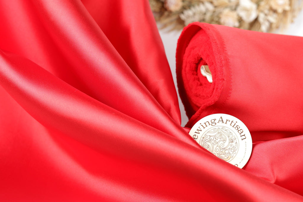 a close-up view of a red fabric, possibly silk, with a label that reads "SewingArtisan" placed on it.