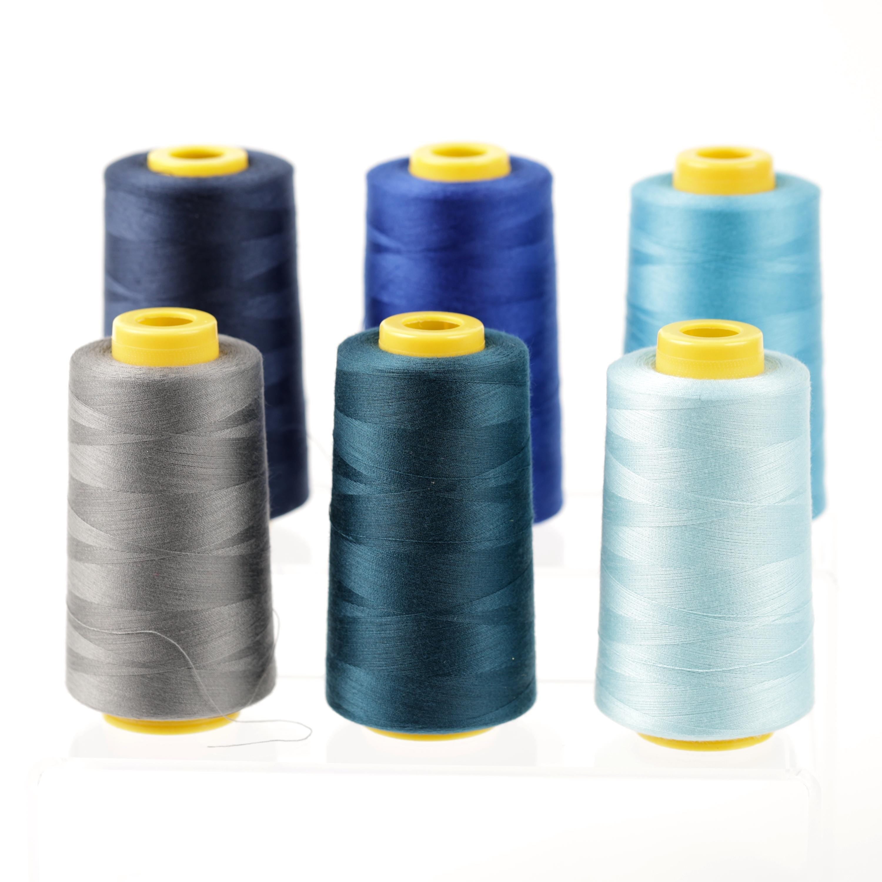 six spools of thread in various colors, including blue, gray, and light blue, arranged in a row.
