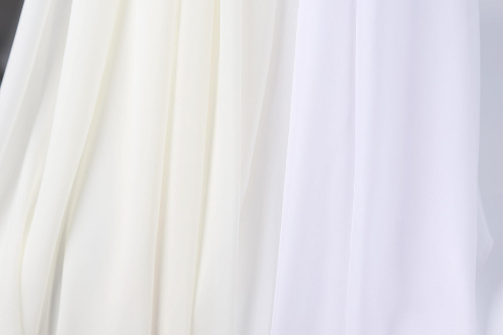 a close-up view of a white fabric, possibly a sheer or sheer-like material, with a subtle texture. The fabric appears to be made of a sheer white material, which could be used for various purposes, such as clothing, home decor, or window treatments. The image does not contain any discernible objects or actions, and the focus is on the fabric's texture and color.