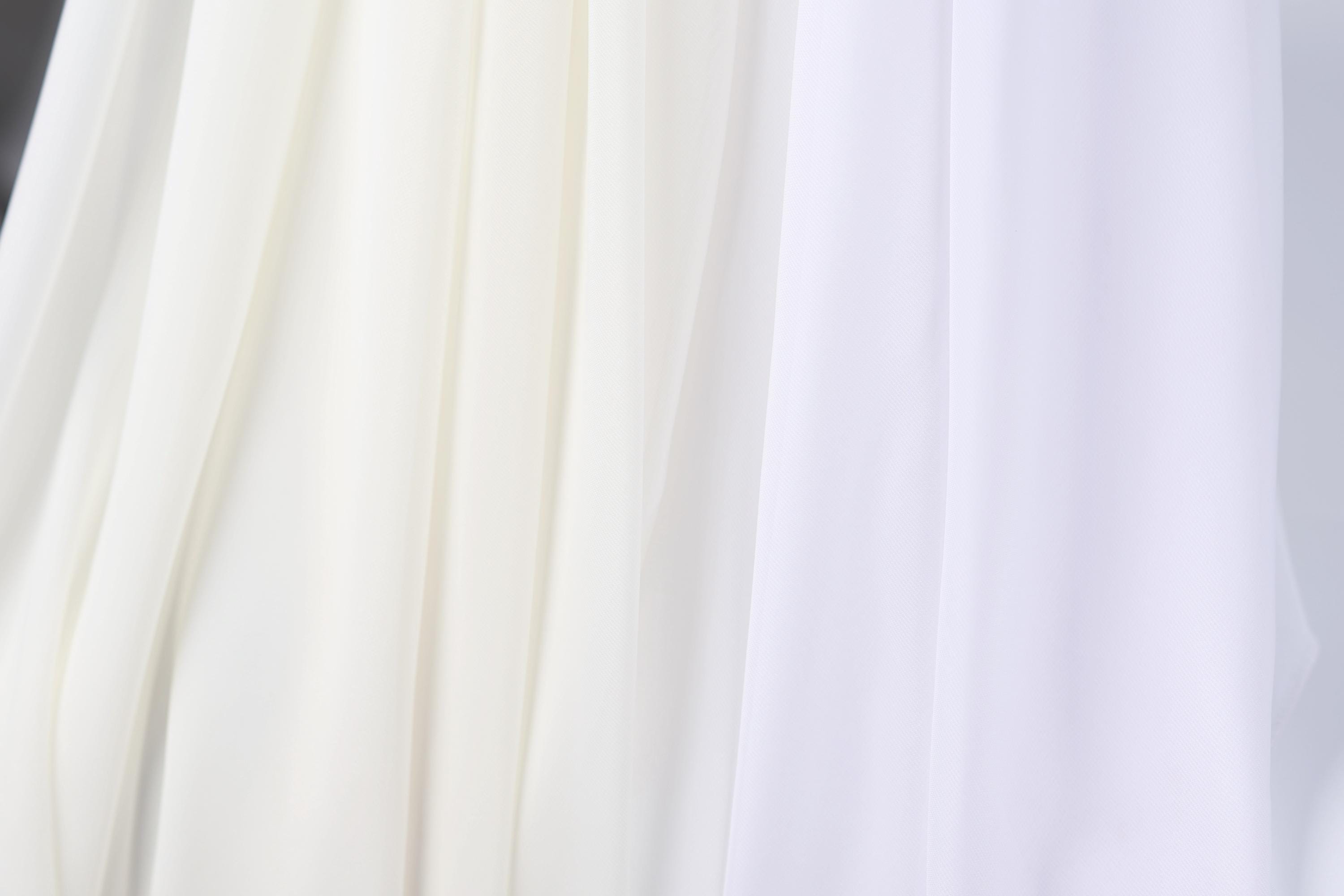 a close-up view of a white fabric, possibly a sheer or sheer-like material, with a subtle texture. The fabric appears to be made of a sheer white material, which could be used for various purposes, such as clothing, home decor, or window treatments. The image does not contain any discernible objects or actions, and the focus is on the fabric's texture and color.