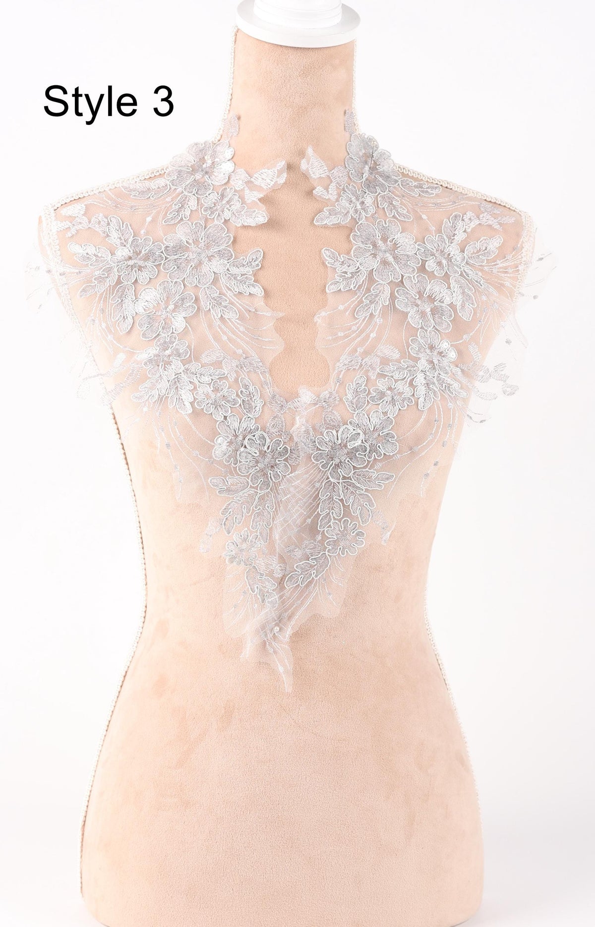 A mannequin wearing a white lace collar with intricate floral patterns.