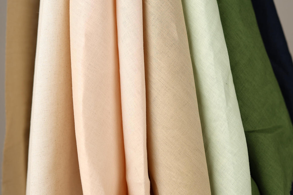 A close-up view of various fabric swatches in different colors, including peach, beige, and green.