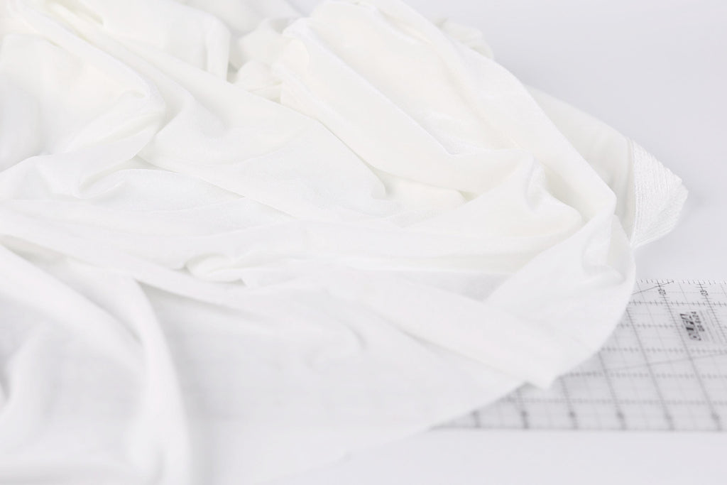 a close-up view of a white fabric, possibly a piece of clothing or a textile, with a ruler visible in the background.