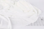 a close-up view of a white fabric, possibly a piece of clothing or a textile, with a ruler visible in the background.