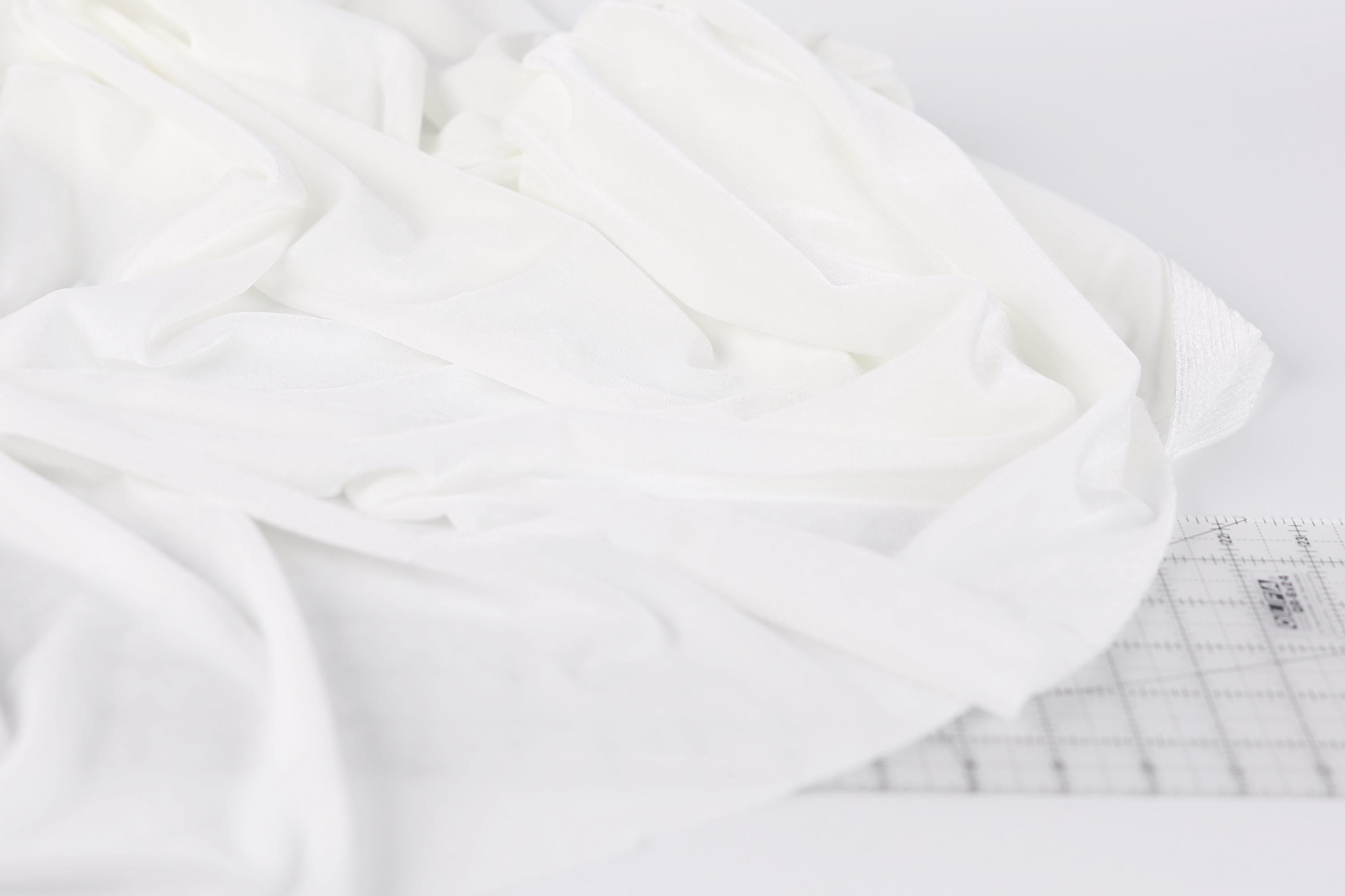 a close-up view of a white fabric, possibly a piece of clothing or a textile, with a ruler visible in the background.