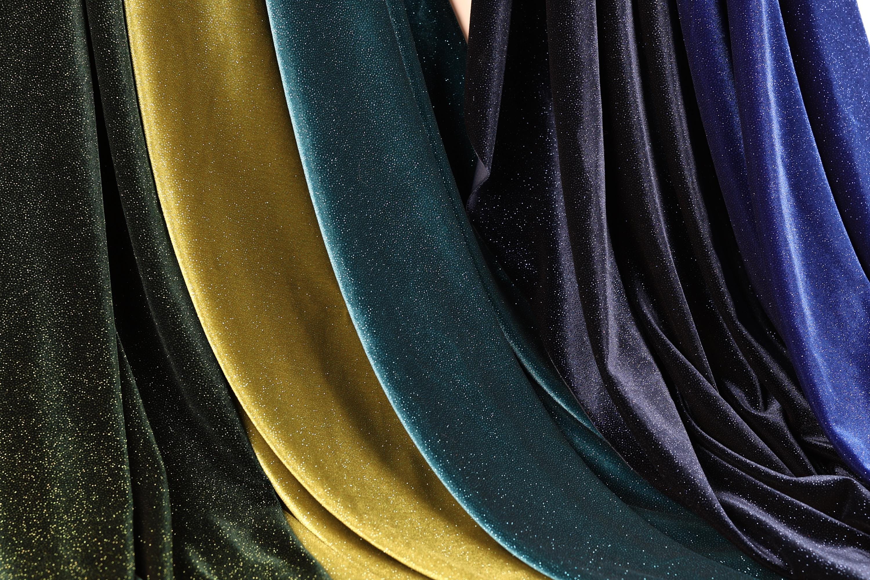 a close-up view of several colorful velvet fabric swatches, with a mix of gold, blue, and black hues.