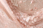 The image is a close-up of a delicate, pink lace fabric adorned with intricate floral patterns and sequins.