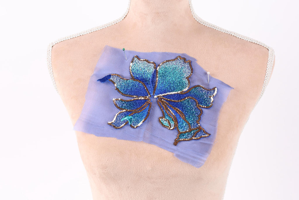 a mannequin torso with a blue and green embroidered flower design on a piece of fabric attached to it.