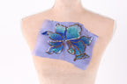a mannequin torso with a blue and green embroidered flower design on a piece of fabric attached to it.