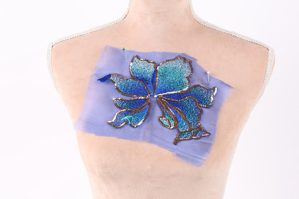a mannequin torso with a blue and green embroidered flower design on a piece of fabric attached to it.