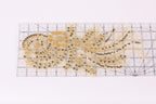 a decorative piece with a gold and black color scheme, including a floral pattern and a swirling design. The piece appears to be a handmade embroidery or beading work, with a ruler visible in the background.