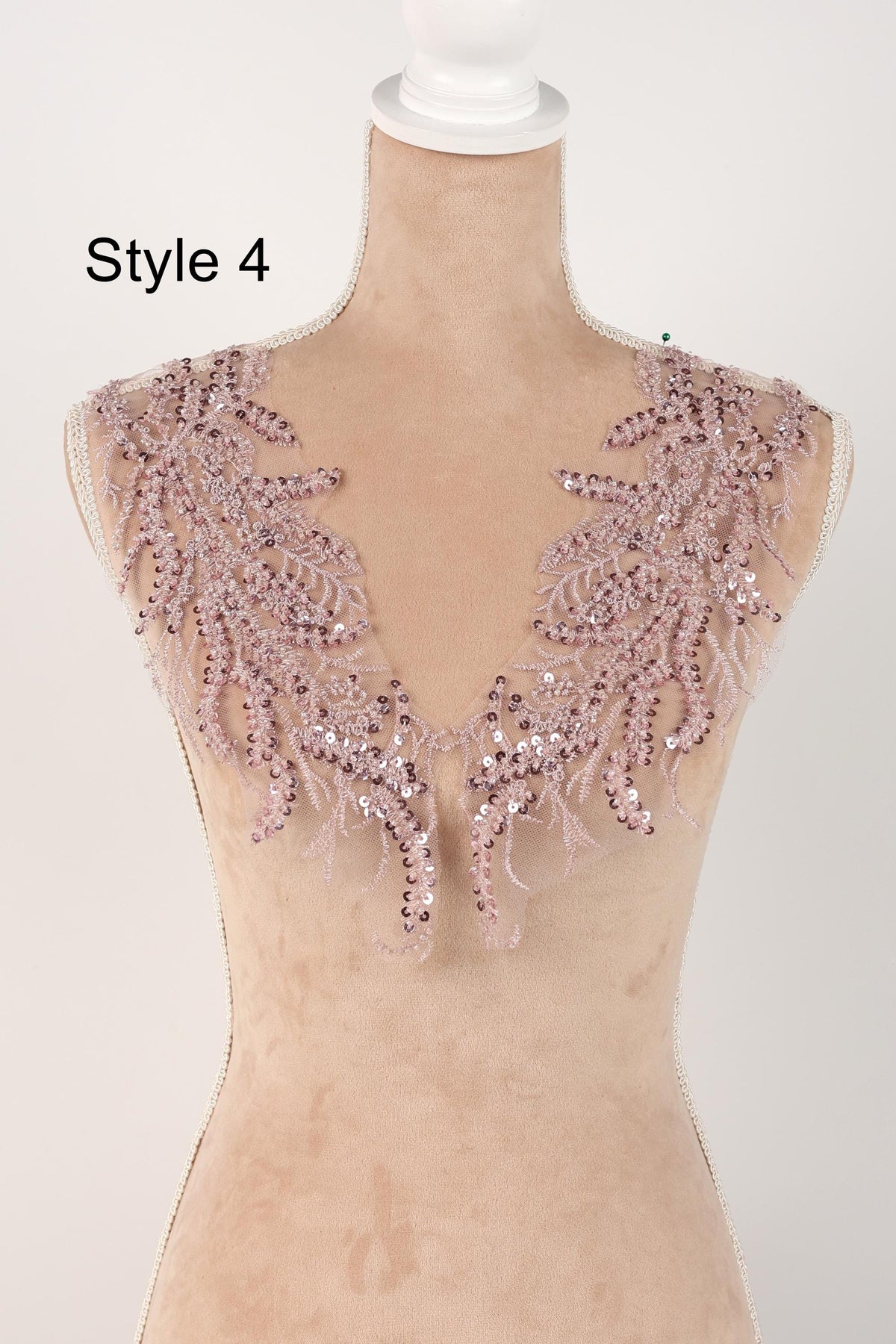 A mannequin wearing a pink sequin and lace collar with a floral pattern.