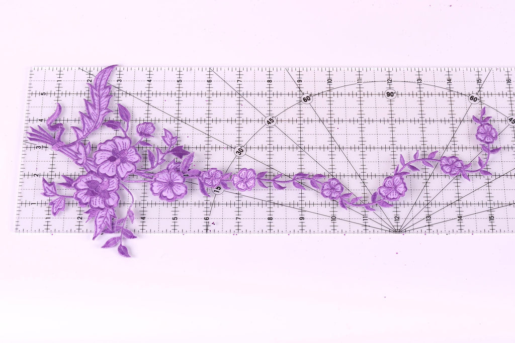 a clear ruler with purple flower designs placed on it.