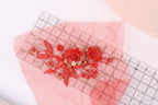a pink fabric with red floral embroidery and a clear ruler placed on top of it.