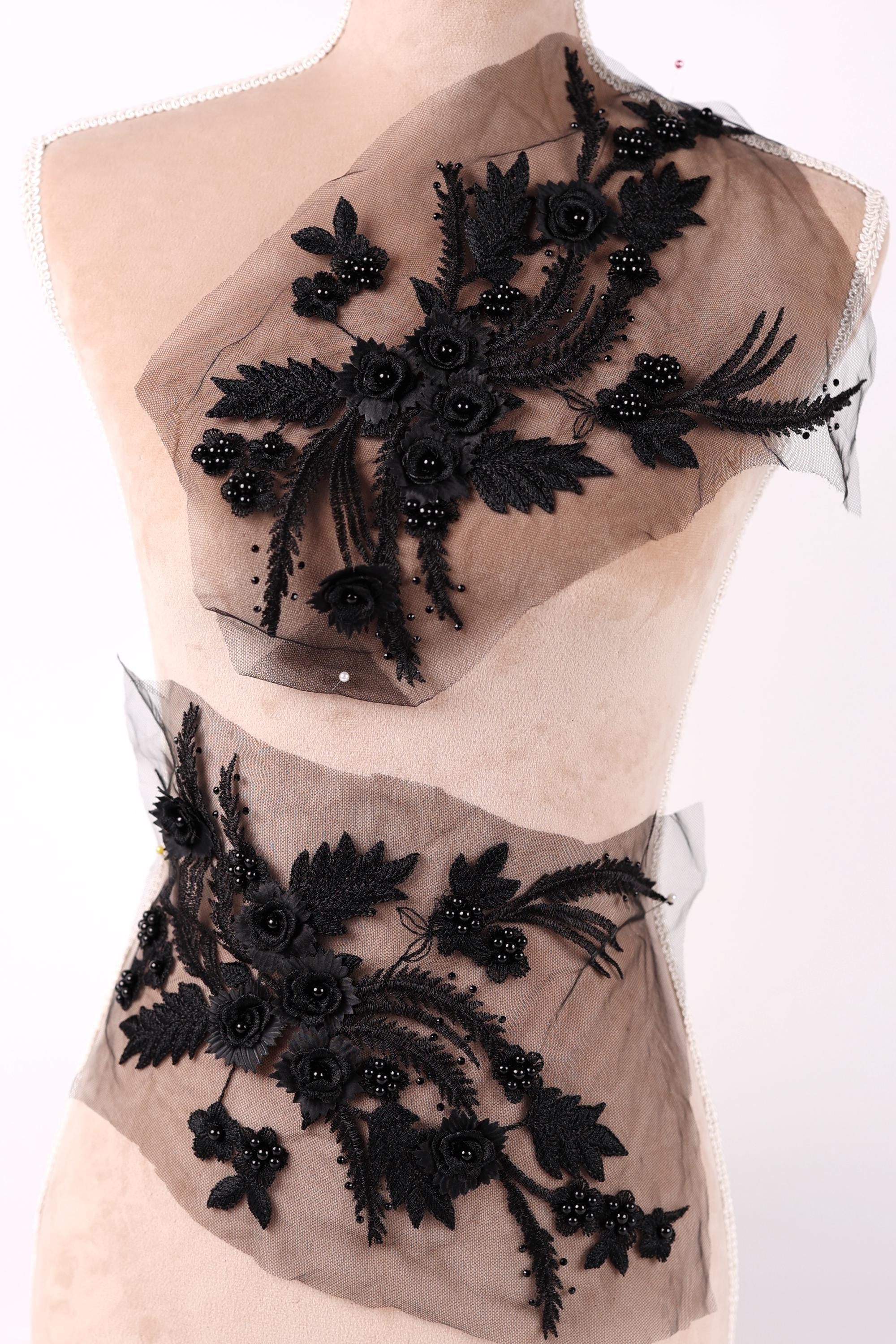 A mannequin wearing a dress with a floral pattern made of black lace and beading.