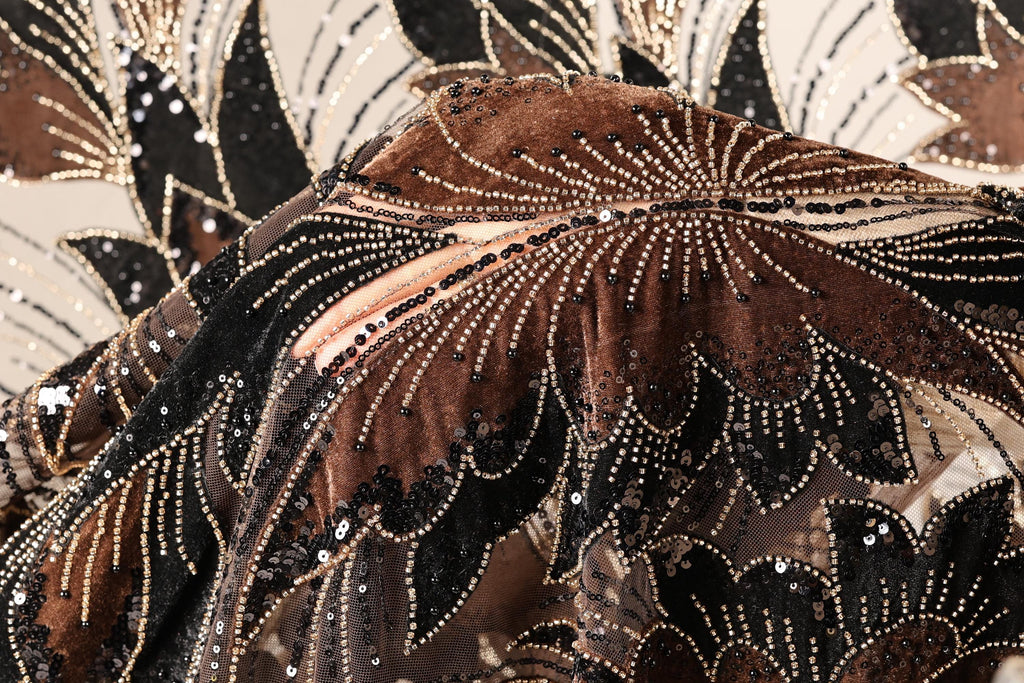 The image is a close-up of a fabric with a floral pattern, featuring a mix of brown, black, and gold colors. The fabric appears to be made of sequin material, with a detailed and intricate design.