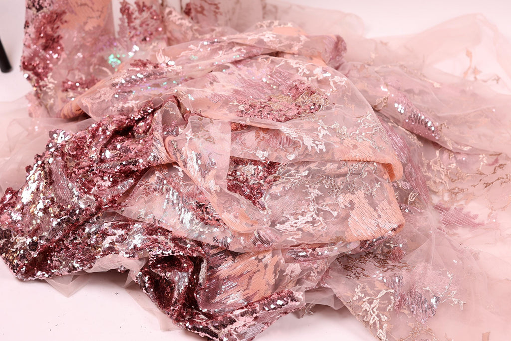 a close-up view of a fabric with pink and white sequin and lace patterns, creating a visually appealing and intricate design.