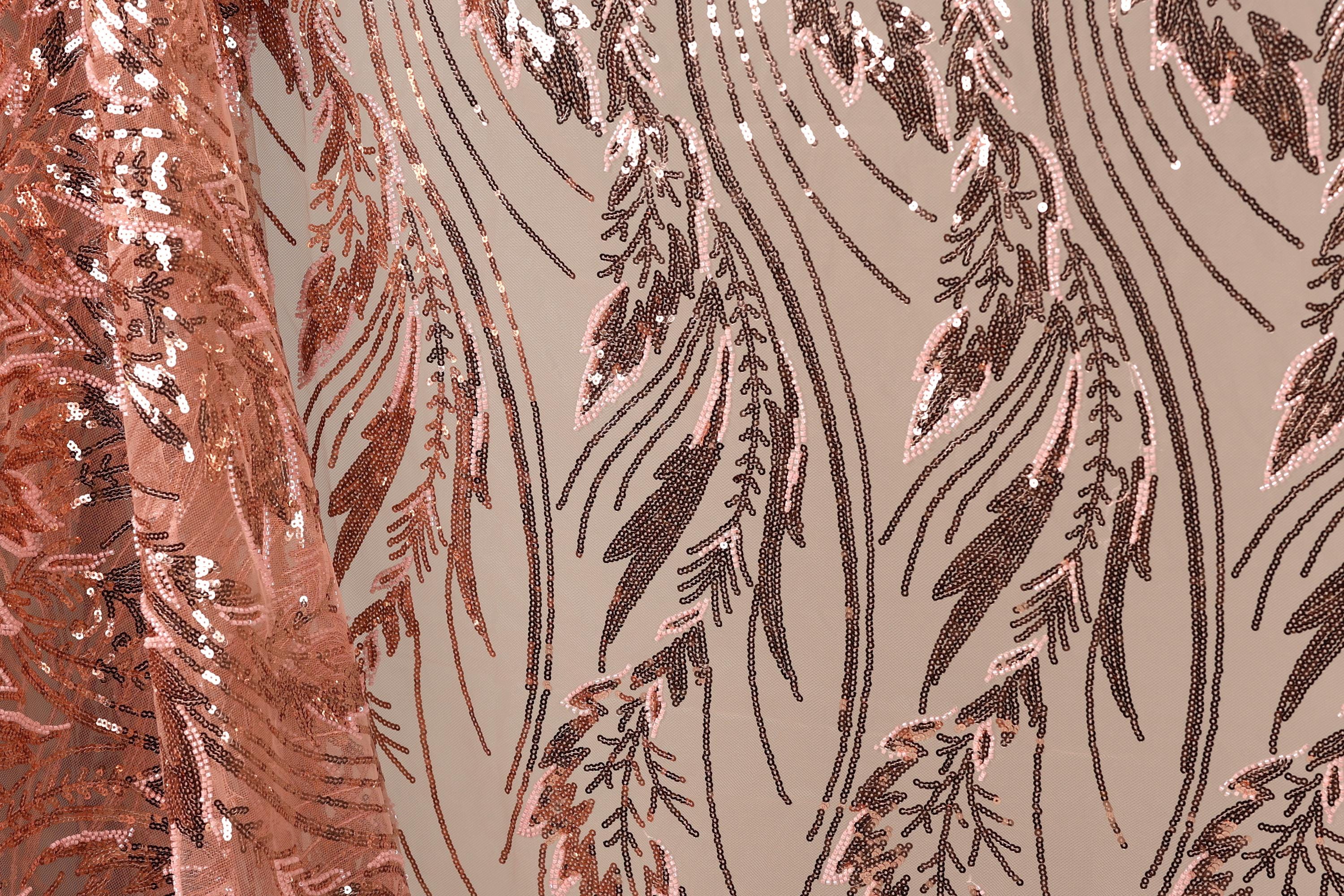 a close-up view of a fabric with a repeating pattern of pink and brown sequin designs. The pattern appears to be a floral or leaf-like design, with the sequins creating a textured and intricate appearance.