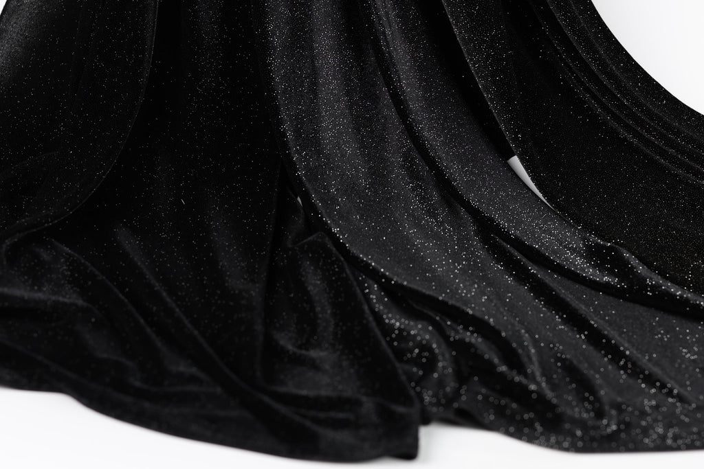 a close-up view of a black velvet fabric with a sparkly texture, creating a shiny and luxurious appearance.