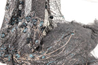 a close-up view of a fabric with intricate blue and black embroidered designs, including flowers and leaves. The fabric appears to be a sheer material, with a dark gray color and a textured pattern.