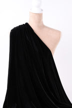 A close-up view of a black velvet fabric draped over a white object, with a white lace detail visible.