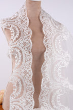 A mannequin wearing a white lace dress with intricate floral patterns.