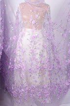 a beautiful dress with a sheer, sheer fabric that is predominantly purple in color. The dress is adorned with a floral pattern, and the fabric appears to be sheer, allowing the delicate purple flowers to be visible. The dress is displayed against a white background, which highlights its vibrant color and intricate design.
