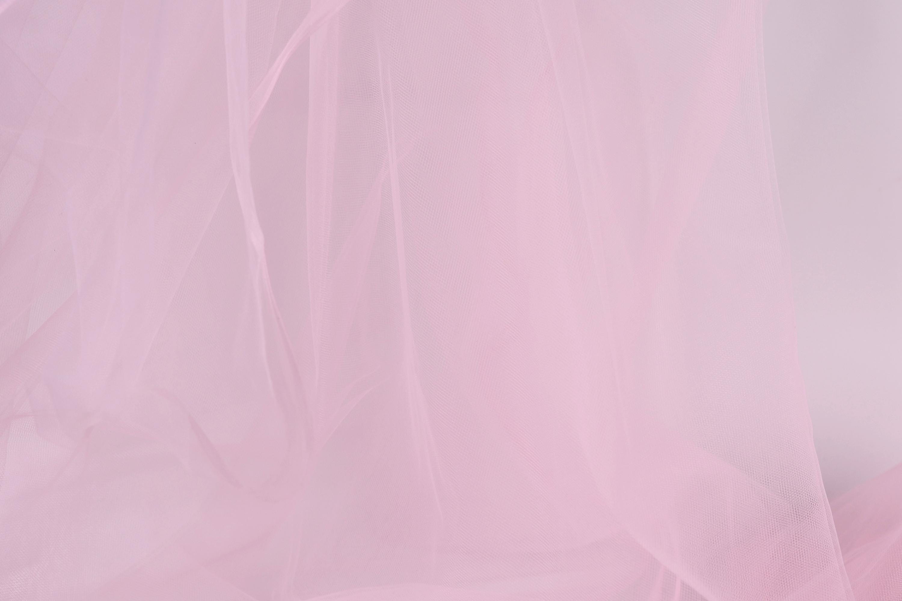 The image is a close-up of a soft, light pink fabric, possibly a sheer or sheer-like material. The fabric appears to be delicate and delicate, with a smooth texture that is visually appealing.