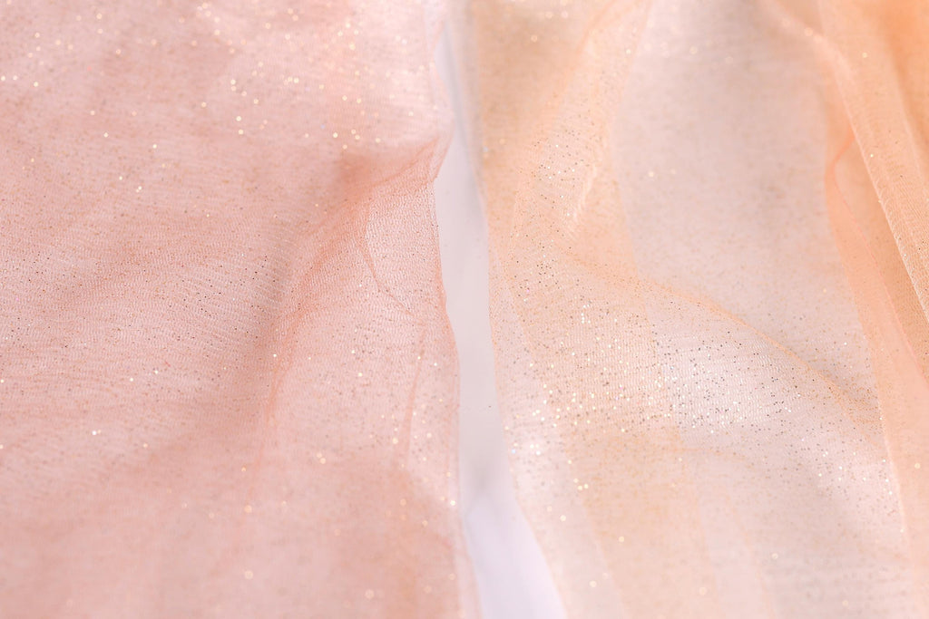 a close-up view of a fabric with a pink and peach-colored background, with a white line running through it.