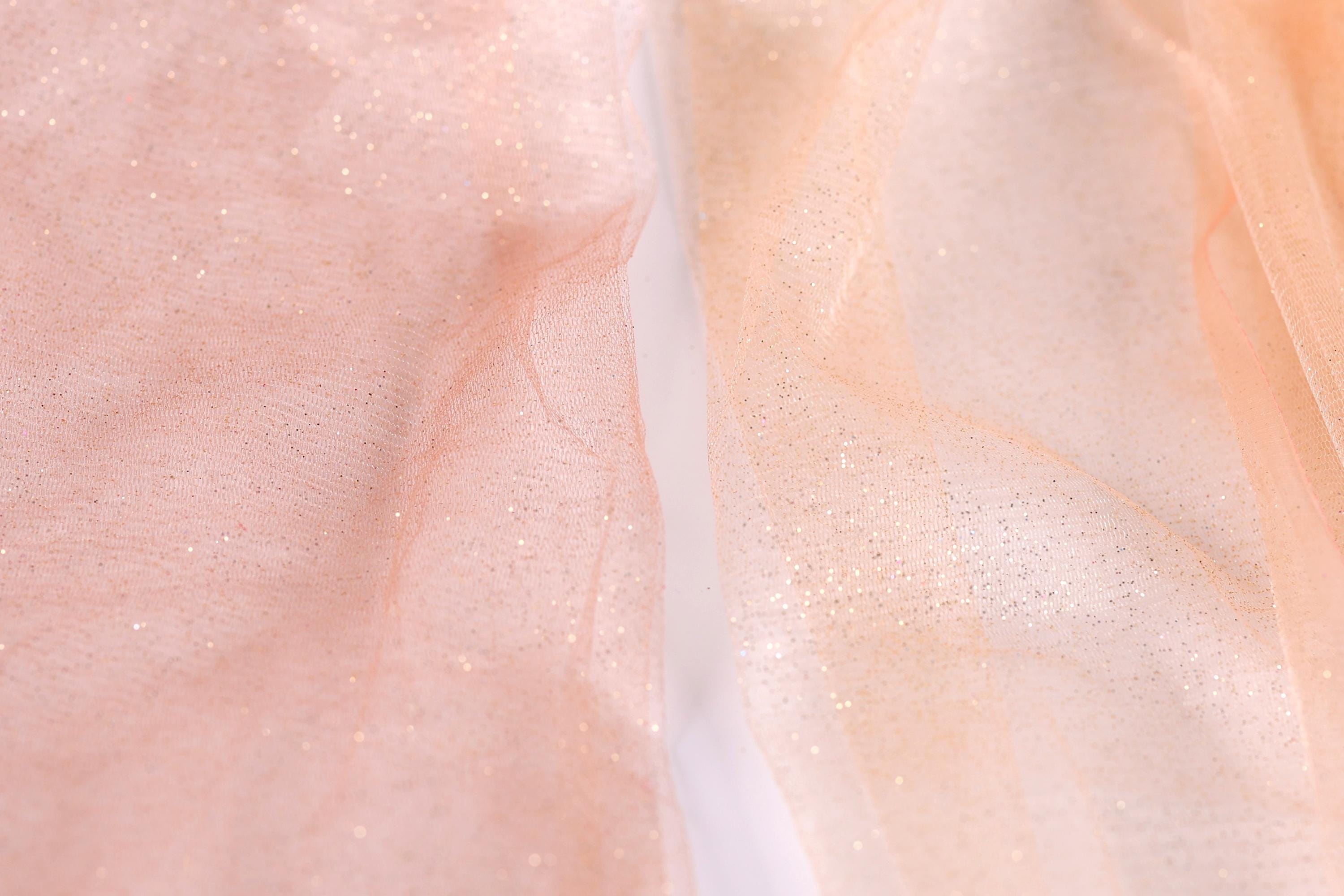 a close-up view of a fabric with a pink and peach-colored background, with a white line running through it.