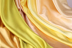 The image is a close-up of a fabric with a vibrant yellow and peach color gradient, creating a visually appealing and textured appearance.