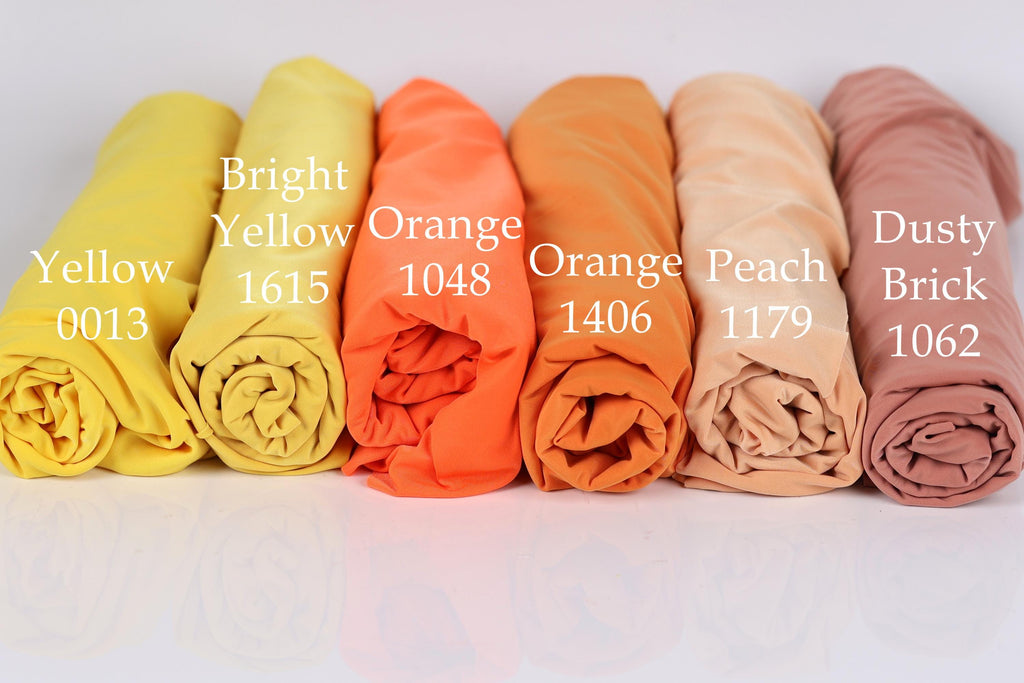 six rolled-up fabric swatches in different colors, including bright yellow, orange, peach, dusty brick, and peach.