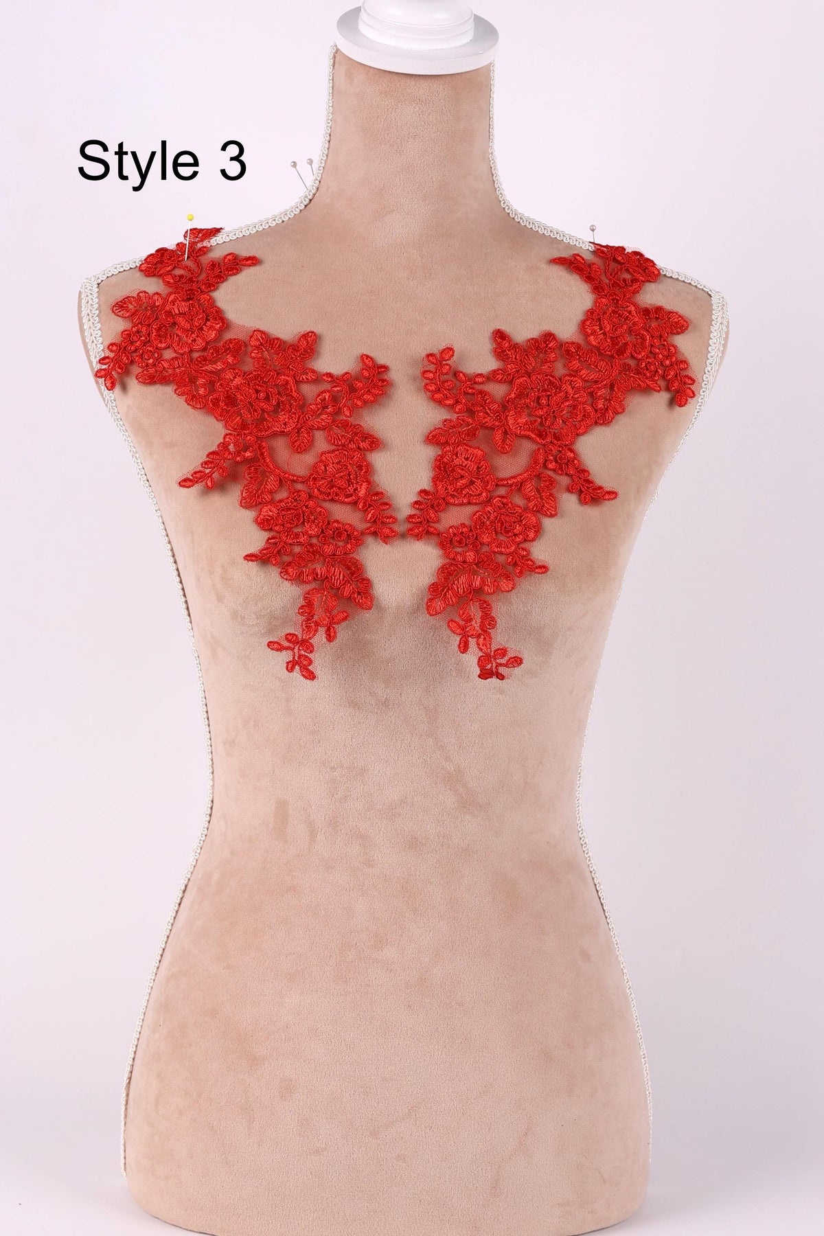 A mannequin wearing a red lace dress with a floral pattern.